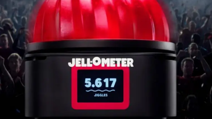 Red gelatin-shaped device labeled "Jellometer" with a digital display in front of a cheering crowd
